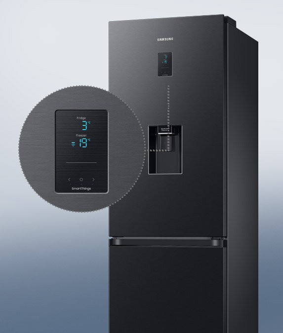 Czytelny wyświetlacz lodówki RB34C652EBN umieszczony na drzwiach Czarna lodówka z wyświetlaczem pokazującym temperaturę: Fridge 3°C, Freezer -19°C. Na drzwiach znajduje się podajnik wody z napisem \'SmartThings\'.
