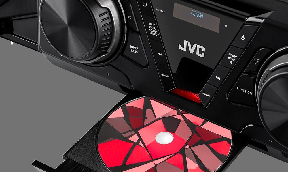 Czarna wieża audio z widocznym logo JVC, wyświetlaczem z napisem \'OPEN\' oraz wysuniętą tacką z kolorową płytą CD. Na panelu znajdują się przyciski i pokrętła, w tym oznaczenie \'SUPER BASS\'.