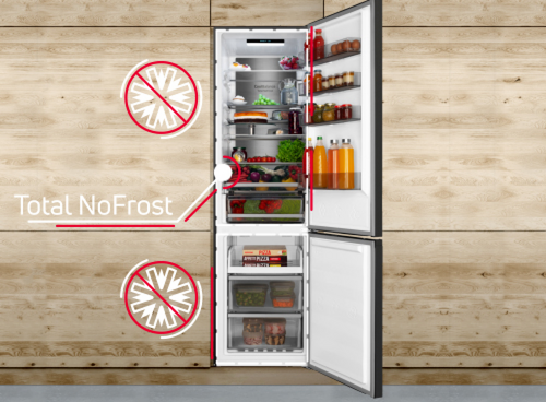 Otwarta biała lodówka z systemem Total NoFrost, wypełniona różnorodnymi produktami spożywczymi, takimi jak owoce, warzywa i napoje. Na drzwiach widoczne są napisy \'Total NoFrost\' oraz symbole wskazujące na funkcję NoFrost.