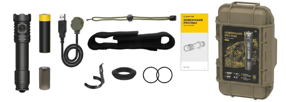 Na obrazie znajduje się zestaw akcesoriów do latarki, w tym latarka, bateria, kabel USB, uchwyt, smycz, etui, pierścienie uszczelniające oraz instrukcja obsługi. Obok widoczna jest twarda walizka z napisem \'DOBERMANN PRO MAX\'.