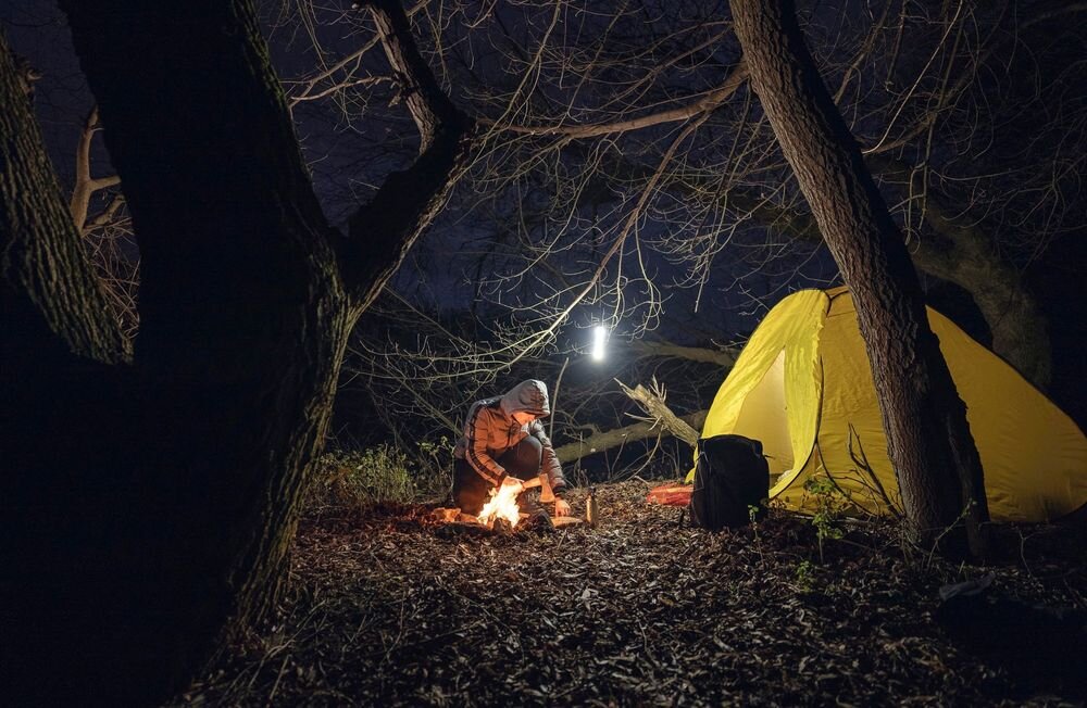 Latarka taktyczna ARMYTEK F08201PC Predator Pro Max Czarny, latarka, zasięg, moc, outdoor, Nocne obozowisko z namiotem i osobą przy ognisku