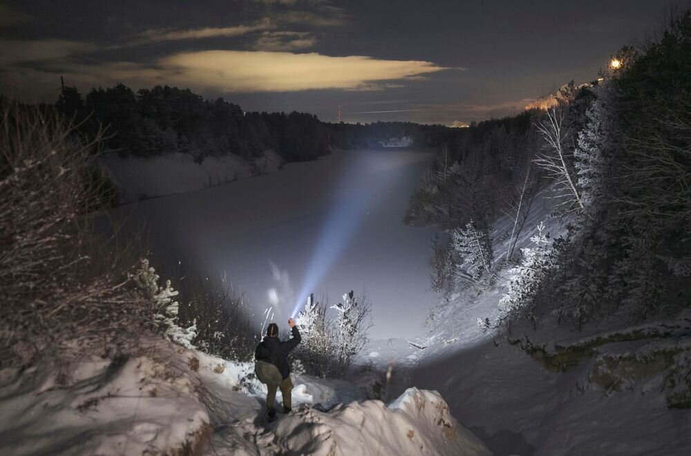 Latarka taktyczna ARMYTEK F08201PC Predator Pro Max Czarny, dioda, reflektor, optyka, jasność, Postać oświetla latarką śnieżny wąwóz w nocy.