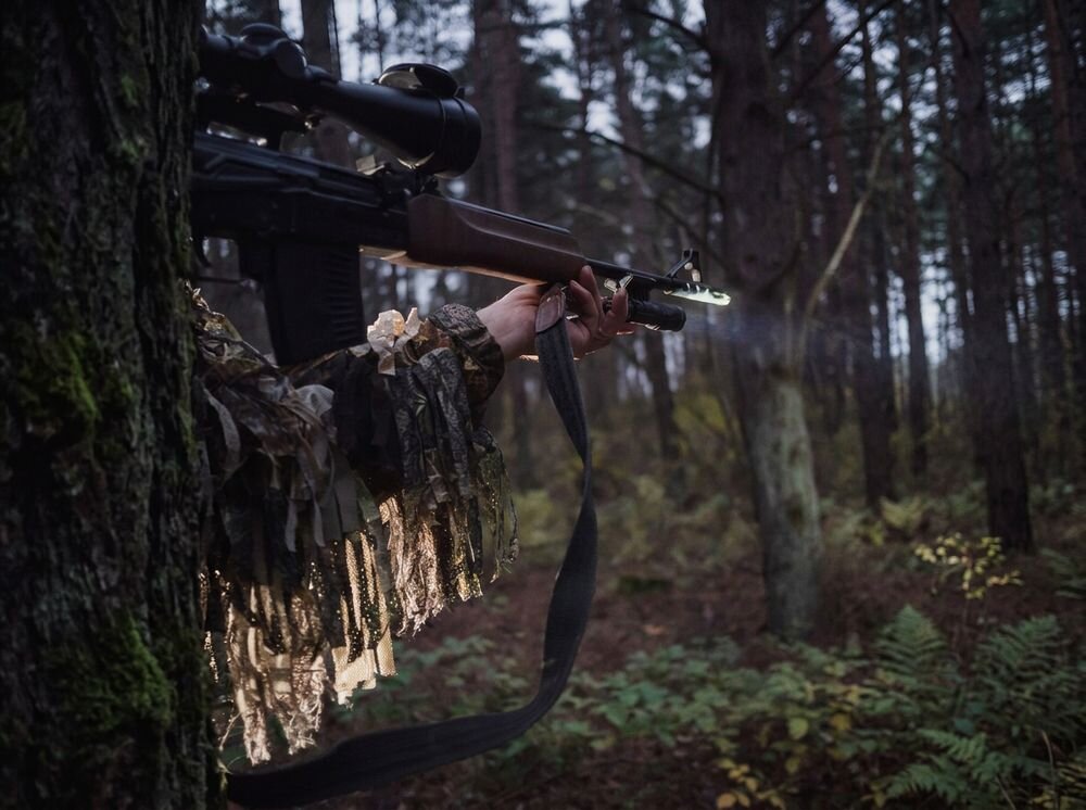 Latarka taktyczna ARMYTEK F02005W, latarka, jasność, dioda, zasięg, Osoba w stroju maskującym celuje z broni w lesie.