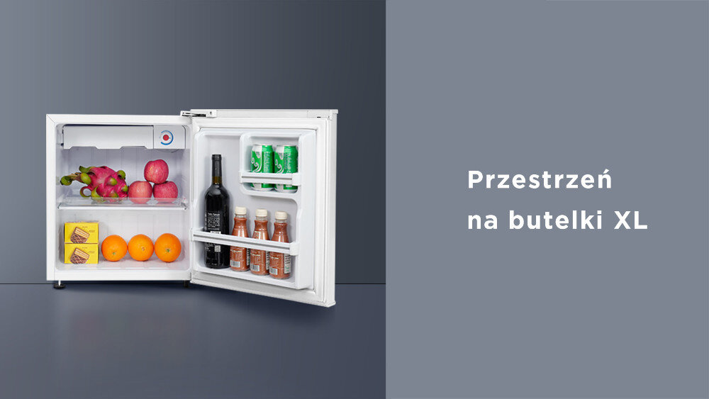 Otwarta biała lodówka z owocami, butelką wina i napojami w puszkach na drzwiach. Obok napis: \'Przestrzeń na butelki XL\'.