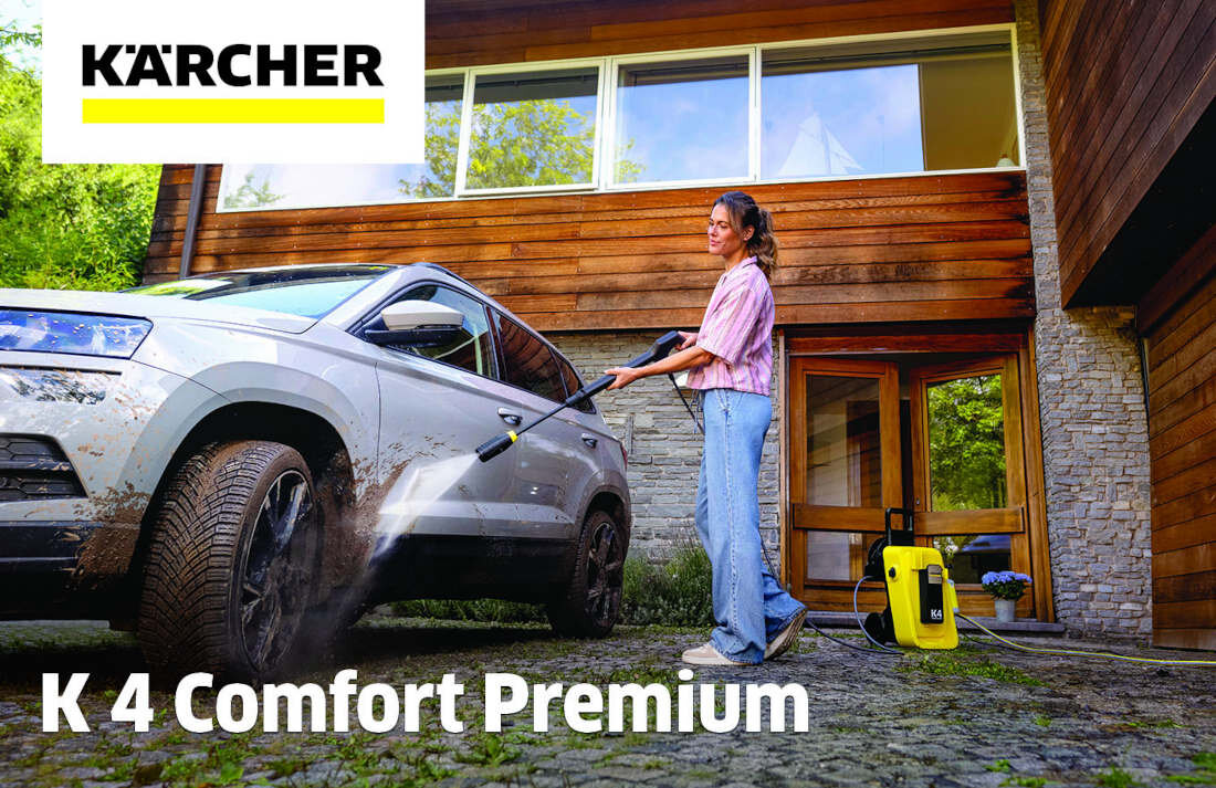Osoba używa myjki ciśnieniowej do czyszczenia samochodu przed domem. Widoczne logo: KÄRCHER, tekst: K 4 Comfort Premium.