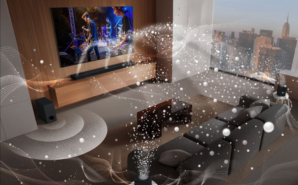 W nowoczesnym salonie znajduje się duży telewizor z wyświetlanym koncertem oraz soundbar umieszczony pod nim. Wokół pokoju widoczne są efekty wizualne symbolizujące dźwięk przestrzenny.