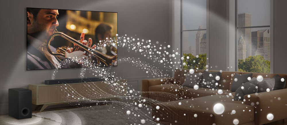 W salonie znajduje się duży telewizor z obrazem muzyka grającego na trąbce, a przed nim ustawiony jest soundbar i subwoofer. Wokół rozchodzą się wizualizacje dźwięku w postaci białych, świetlistych kul.