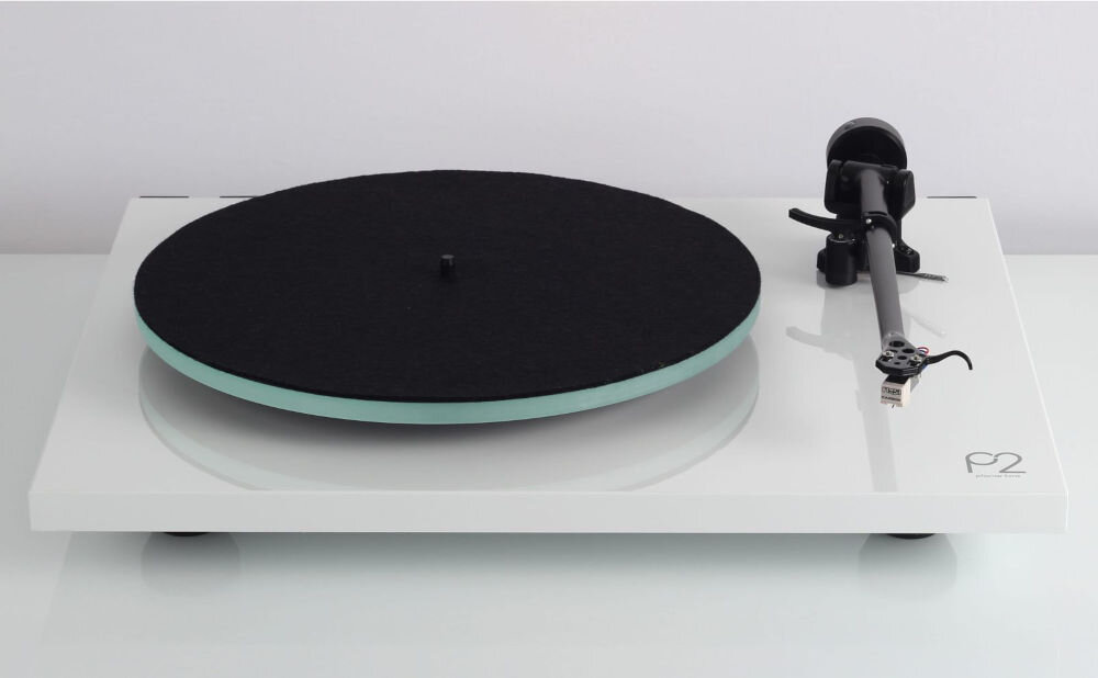 Na obrazie widoczny jest gramofon z białą podstawą i czarnym talerzem. W prawym dolnym rogu znajduje się logo \'P2\'.
