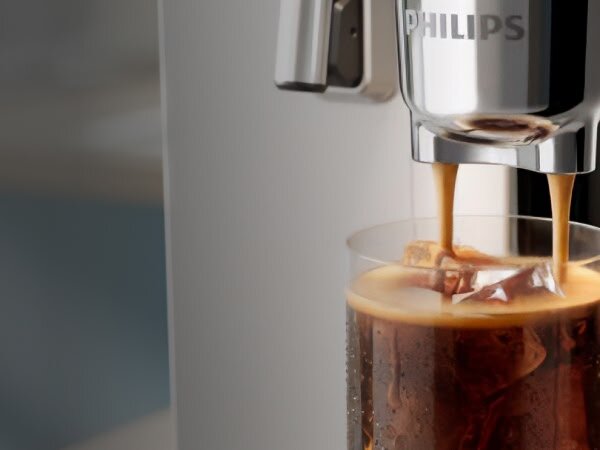 Ekspres do kawy nalewa napój do szklanki z lodem. Na urządzeniu widoczne jest logo \'PHILIPS\'.