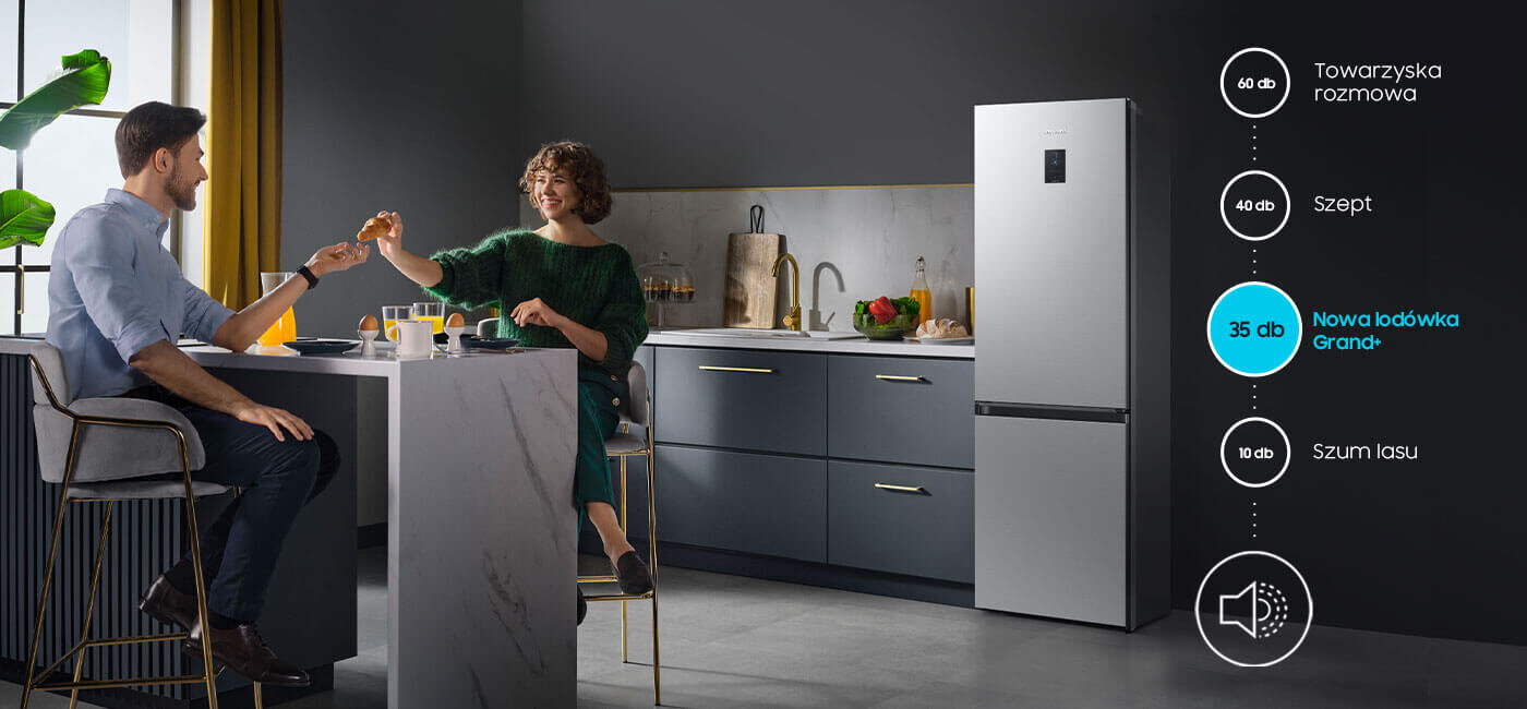 Nowoczesna kuchnia z lodówką Samsung z serii Grand+, której natężenie dźwięku to jedyne 35 dB W nowoczesnej kuchni przy stole siedzi para, a obok stoi lodówka w metalicznym grafitowym kolorze. Obok lodówki znajduje się grafika z poziomami hałasu: 60 dB Towarzyska rozmowa, 40 dB Szept, 35 dB Nowa lodówka Grand+, 10 dB Szum lasu.