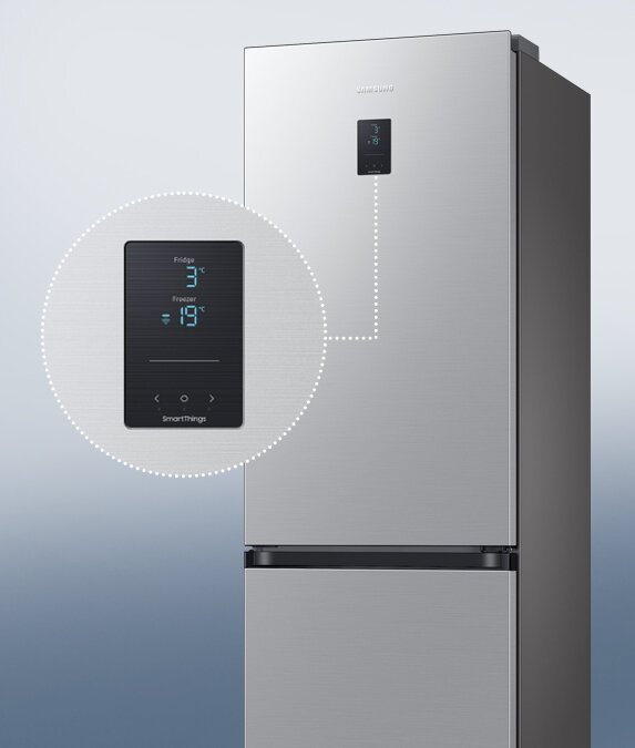 Prezentacja zewnętrznego wyświetlacza na panelu frontowym lodówki Samsung Grand+ Lodówka w kolorze metalicznego grafitu z wyświetlaczem pokazującym temperaturę: Fridge 3°C, Freezer -19°C. Na wyświetlaczu widoczny jest napis \'SmartThings\'.
