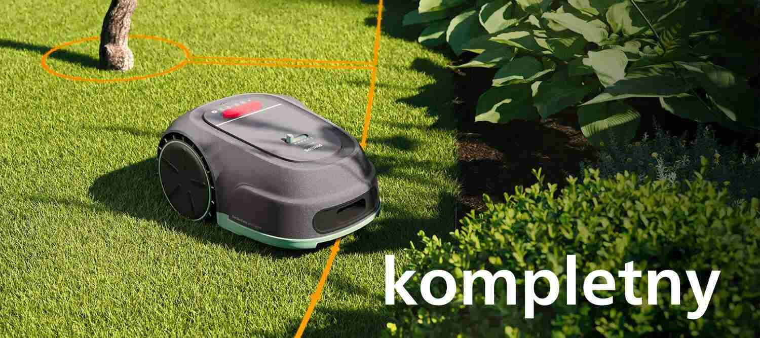 Robot koszący na trawie z widoczną pomarańczową linią prowadzącą. Na obrazie znajduje się tekst: \'kompletny\'.