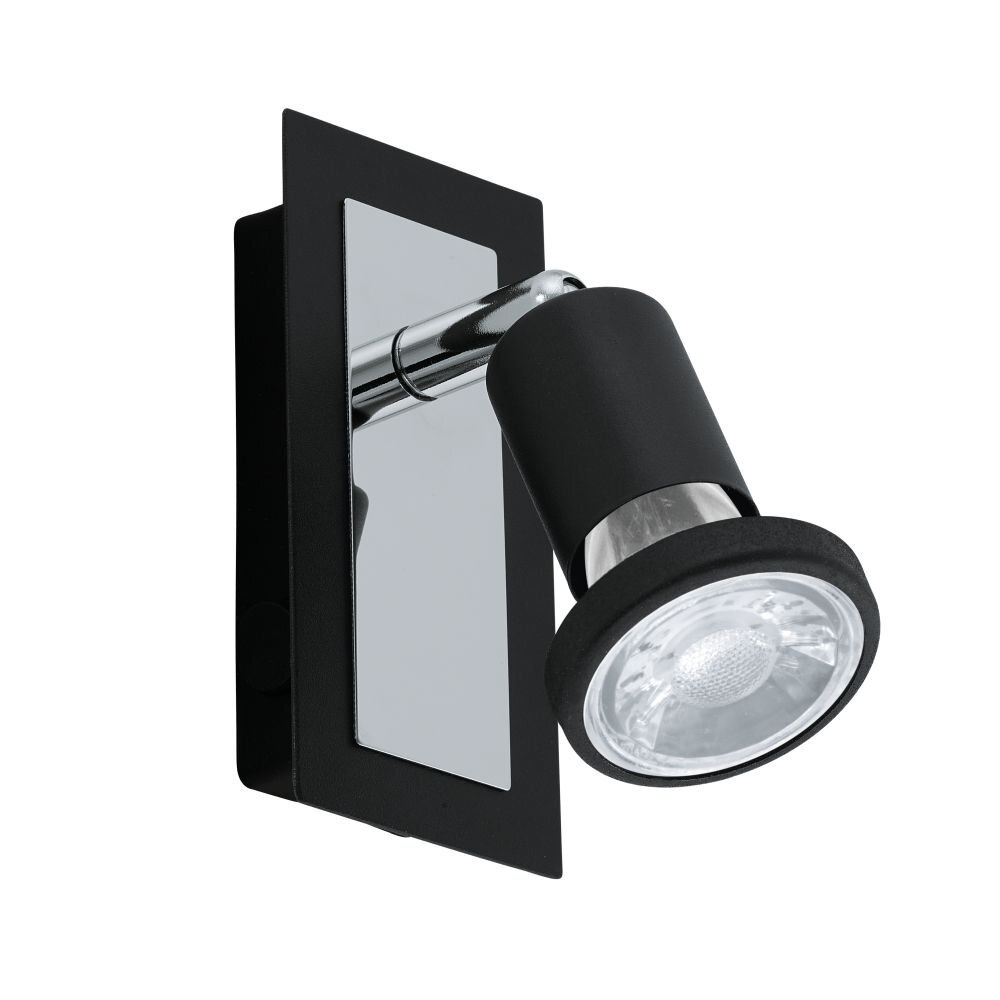 Na obrazie widoczna jest czarna lampa spot z metalicznymi elementami, zamontowana na prostokątnej podstawie. Lampa ma cylindryczny kształt z przezroczystym kloszem.