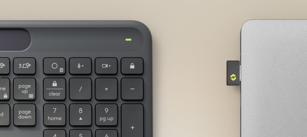 Na obrazie widoczna jest część klawiatury z klawiszami numerycznymi oraz urządzenie z podłączonym adapterem USB. Klawiatura ma ciemny kolor, a na adapterze widnieje logo w kolorze zielonym.