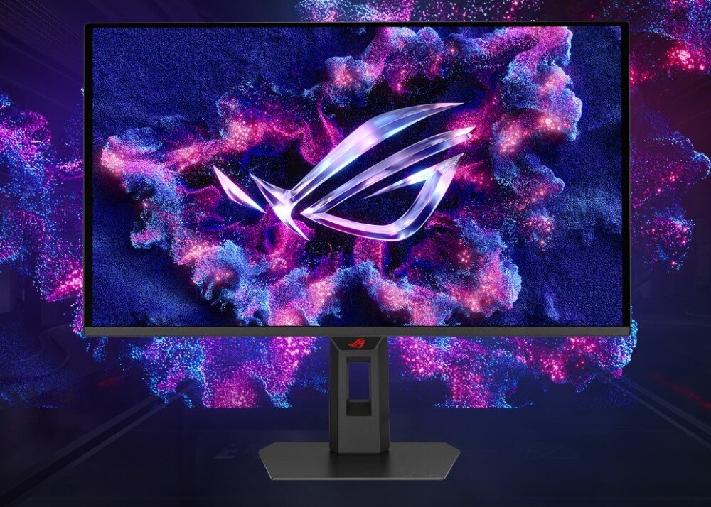 Monitor z wyświetlaczem pokazującym kolorową grafikę z logo ROG na tle abstrakcyjnych wzorów. Podstawa monitora ma prostokątny kształt z widocznym logo ROG.