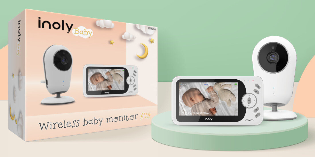 Na obrazie znajduje się elektroniczna niania z kamerą i monitorem, obok opakowania z napisem \'inoly Baby Wireless baby monitor AVA\'. Monitor pokazuje obraz śpiącego dziecka.