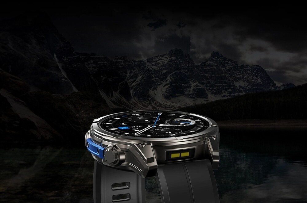 Smartwatch z czarnym paskiem i metalową kopertą, wyświetlający tarczę z różnymi wskaźnikami. W tle widoczne są góry i ciemne niebo.