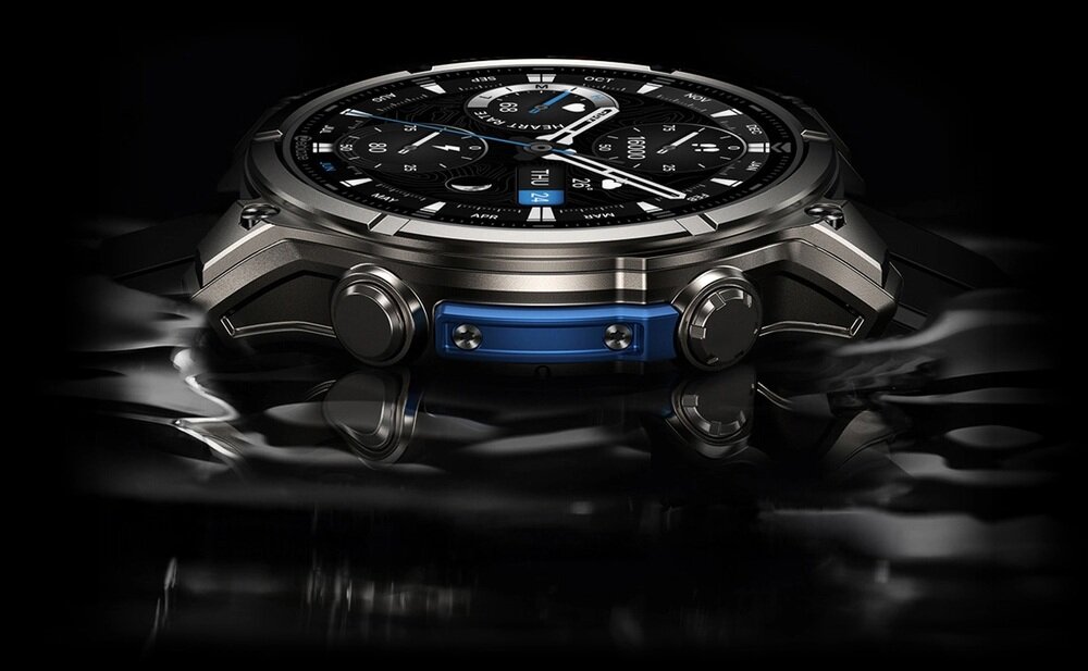 Smartwatch z metalową kopertą i czarnym wyświetlaczem, leży na powierzchni przypominającej wodę. Na tarczy widoczne są różne wskaźniki i cyfry.