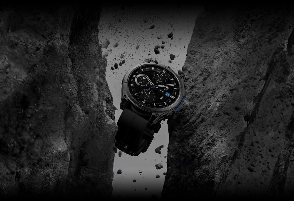 Czarny smartwatch z okrągłą tarczą zawieszony pomiędzy dwoma skalnymi ścianami, otoczony unoszącymi się drobinami skał.