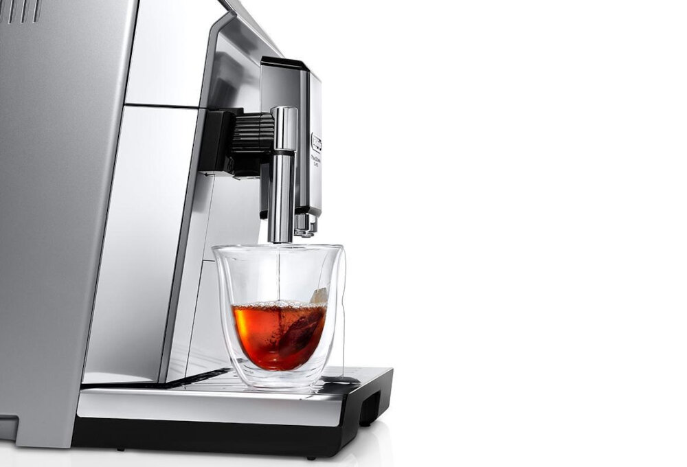 Srebrny ekspres do kawy z przezroczystą szklanką, w której znajduje się napój. Na ekspresie widoczne jest logo \'DeLonghi\'.