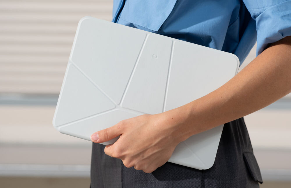 Osoba trzyma szare etui na tablet z geometrycznym wzorem. Etui jest prostokątne i ma zaokrąglone rogi.