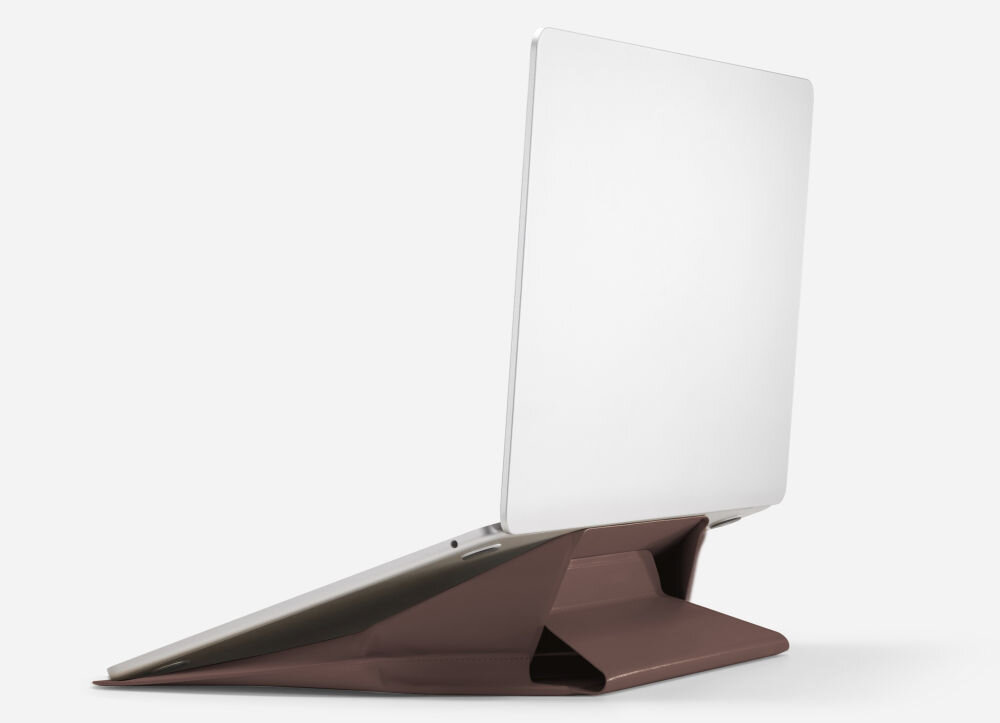 Na obrazie widoczny jest laptop umieszczony na ciemnobrązowej podstawce, która pełni funkcję stojaka. Laptop jest otwarty, a podstawa ma geometryczny kształt.