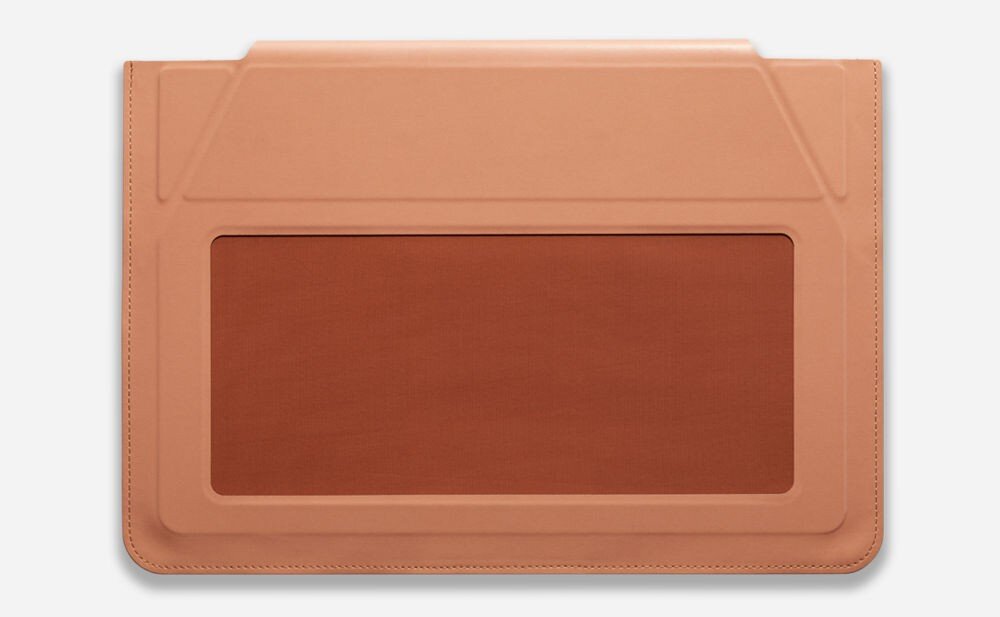 Na obrazie widoczna jest brązowa torba na laptopa z prostokątnym wycięciem na środku, wykonana z materiału przypominającego skórę.