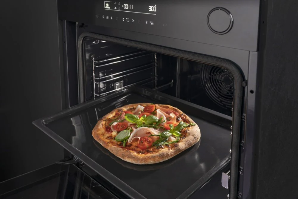 Otwarty piekarnik z widoczną pizzą na blasze. Na panelu piekarnika wyświetlają się cyfry \'300\'.