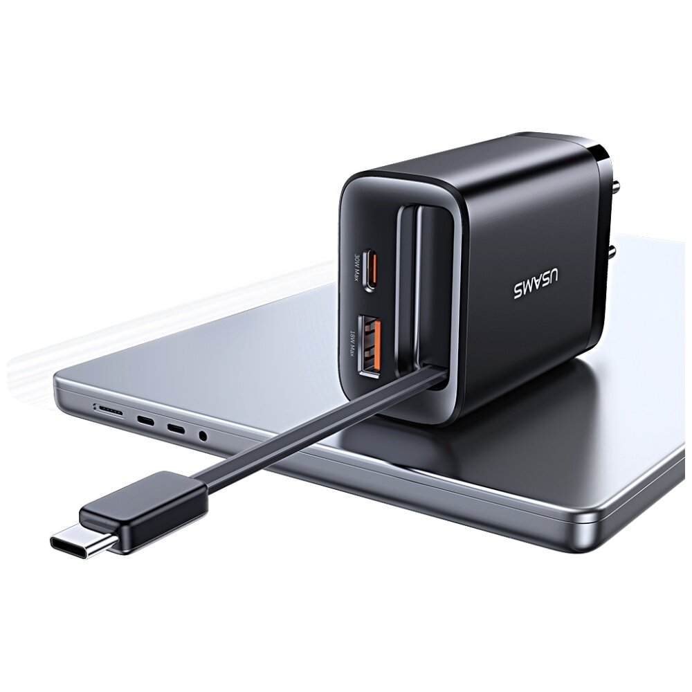 Czarna ładowarka sieciowa z dwoma portami (USB-C i USB-A) oraz podłączonym kablem USB-C leży na srebrnym laptopie. Na ładowarce widoczne jest logo \'USAMS\'.
