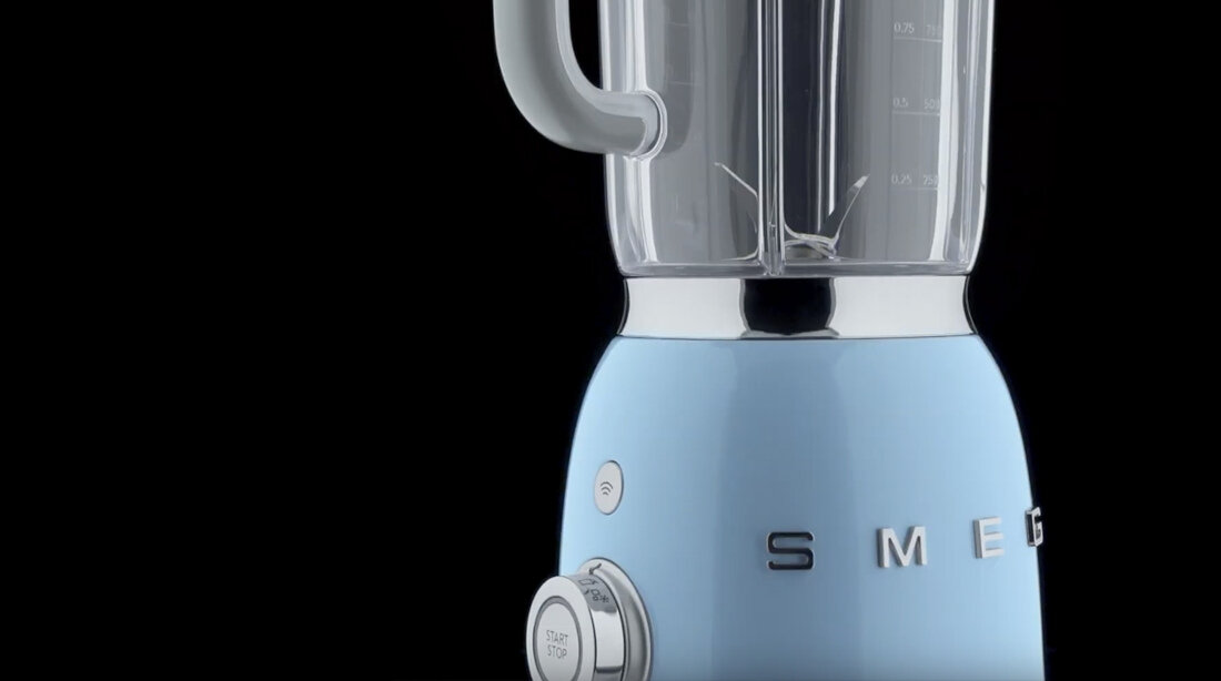 Blender kielichowy w pastelowym kolorze z widocznym logo \'SMEG\' na obudowie. Posiada pokrętło z napisem \'Start/Stop\'.