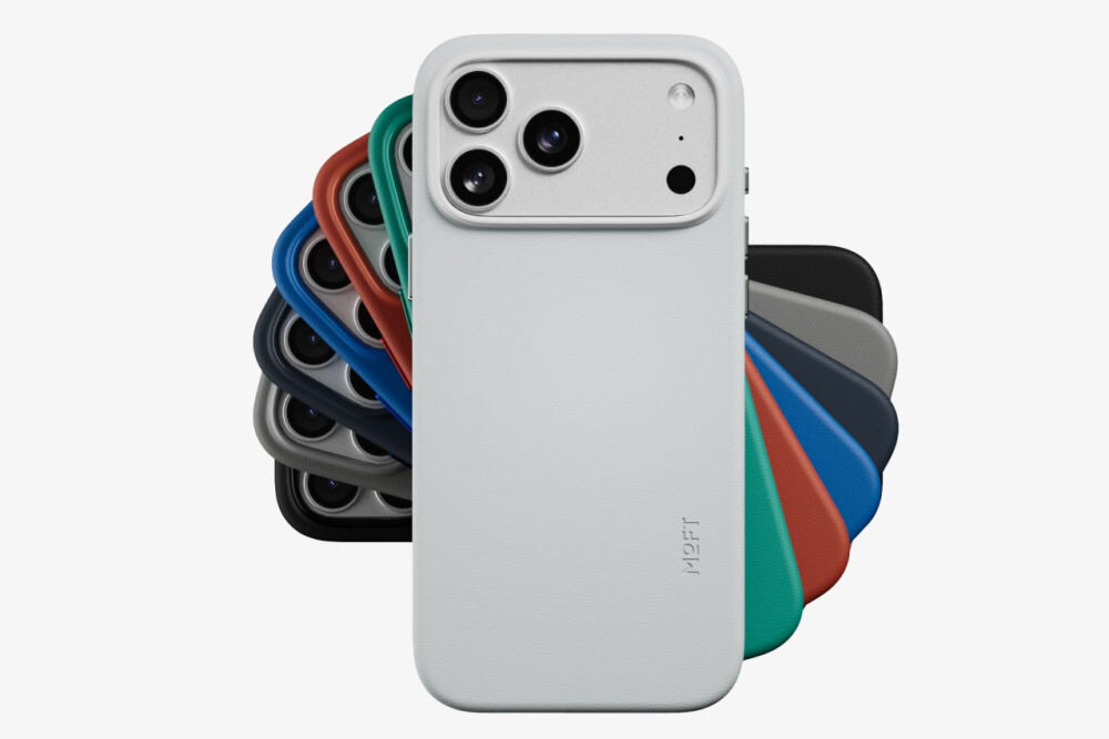 Na obrazie widoczne jest etui na telefon w kolorze czarnym z napisem \'MOFT\', otoczone przez inne etui w różnych kolorach. Etui ma wycięcia na trzy obiektywy aparatu i dodatkowe otwory na inne elementy telefonu.