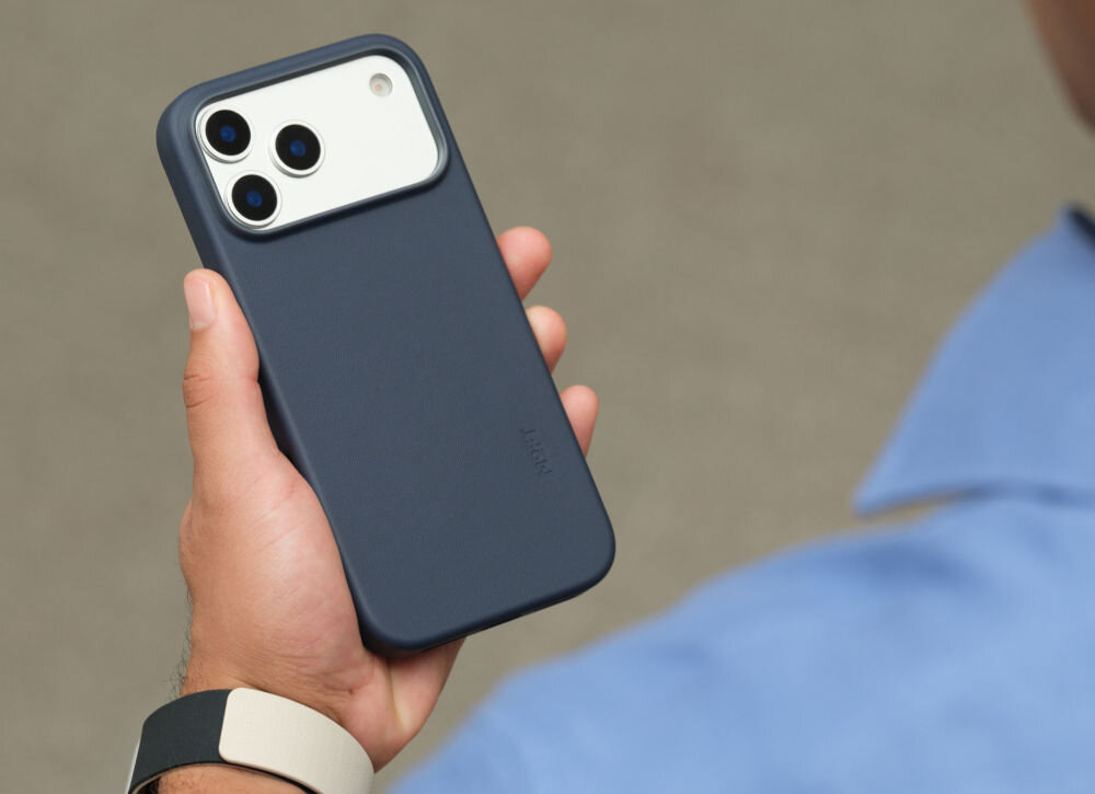 Osoba trzyma granatowe etui na telefon z trzema widocznymi obiektywami aparatu. Na etui widoczny jest napis \'MOFT\'.