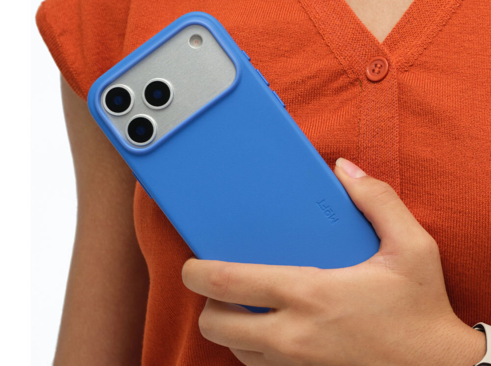 Osoba trzyma telefon w niebieskim etui z trzema widocznymi obiektywami aparatu. Na etui widoczny jest napis \'MOFT\'.