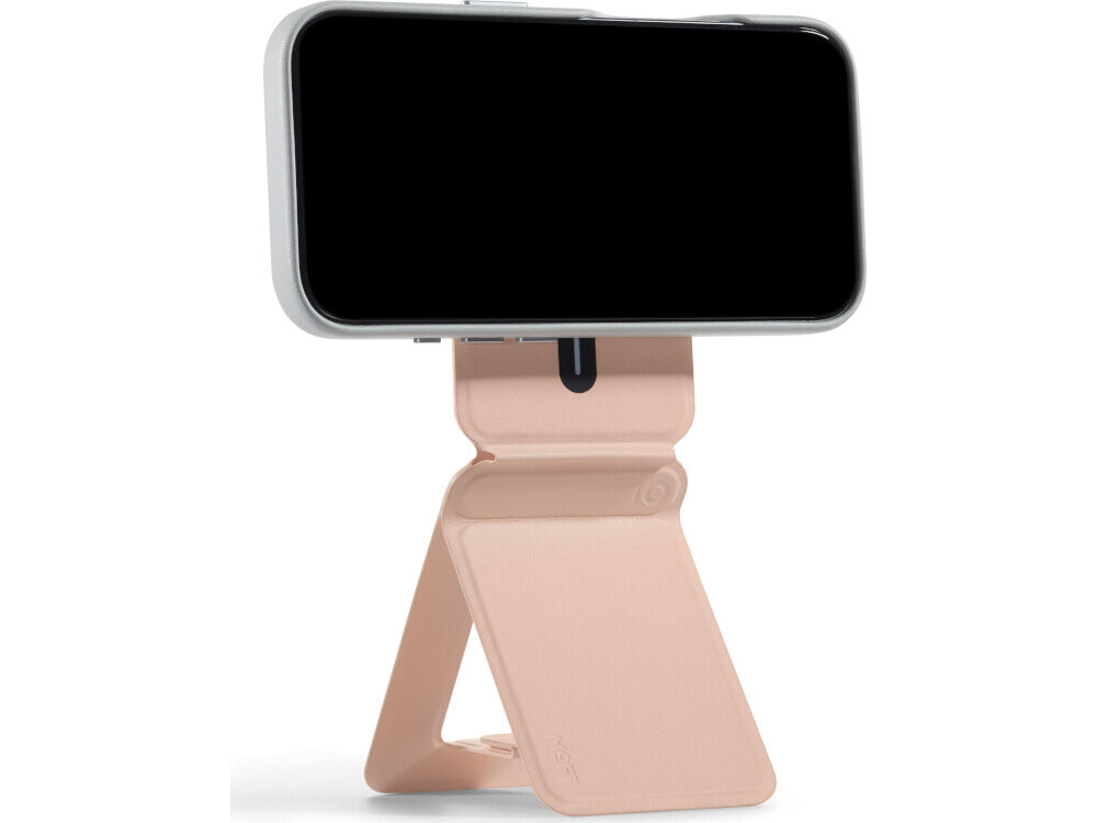 Na obrazie widoczny jest brzoskwiniowy stojak na telefon z funkcją magnetycznego portfela. Telefon jest umieszczony poziomo na stojaku, a na produkcie widnieje logo \'MOFT\'.