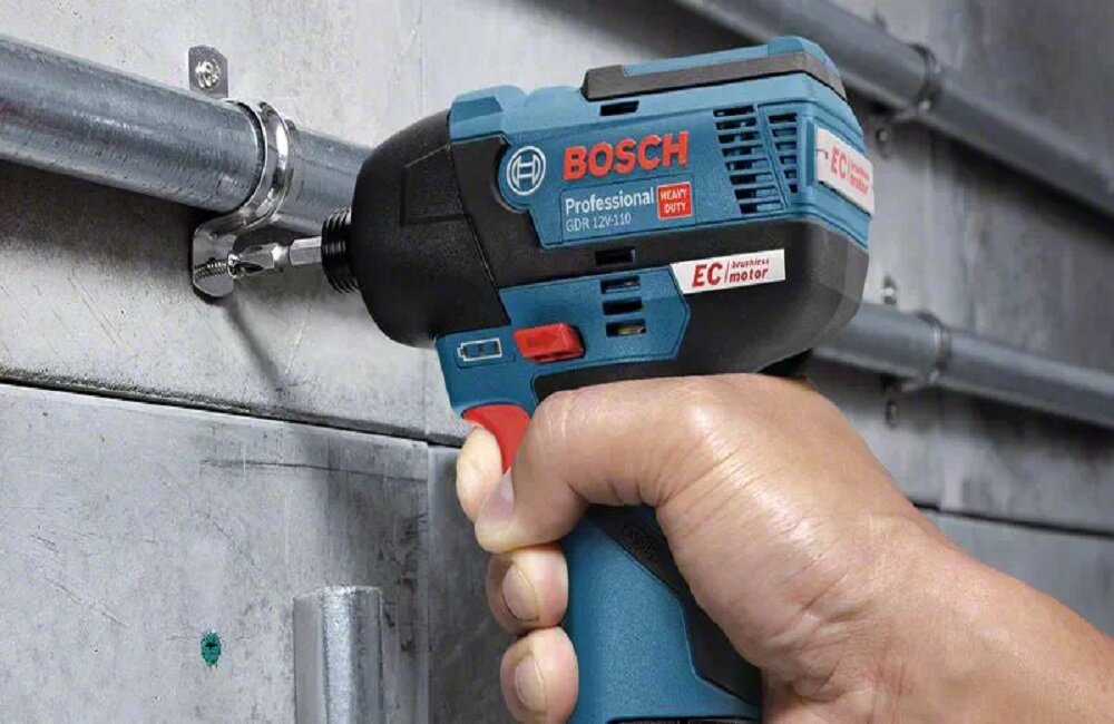 Osoba trzyma niebieski klucz udarowy marki BOSCH, model GDR 12V-110, przykręcając metalowy element do ściany. Na narzędziu widoczne są napisy: \'BOSCH Professional GDR 12V-110\' oraz \'EC brushless motor\'.
