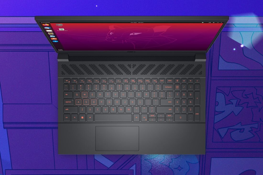 Laptop z widoczną klawiaturą i ekranem, na którym wyświetlany jest system operacyjny z ikonami po lewej stronie. Tło jest w odcieniach fioletu z geometrycznymi wzorami.