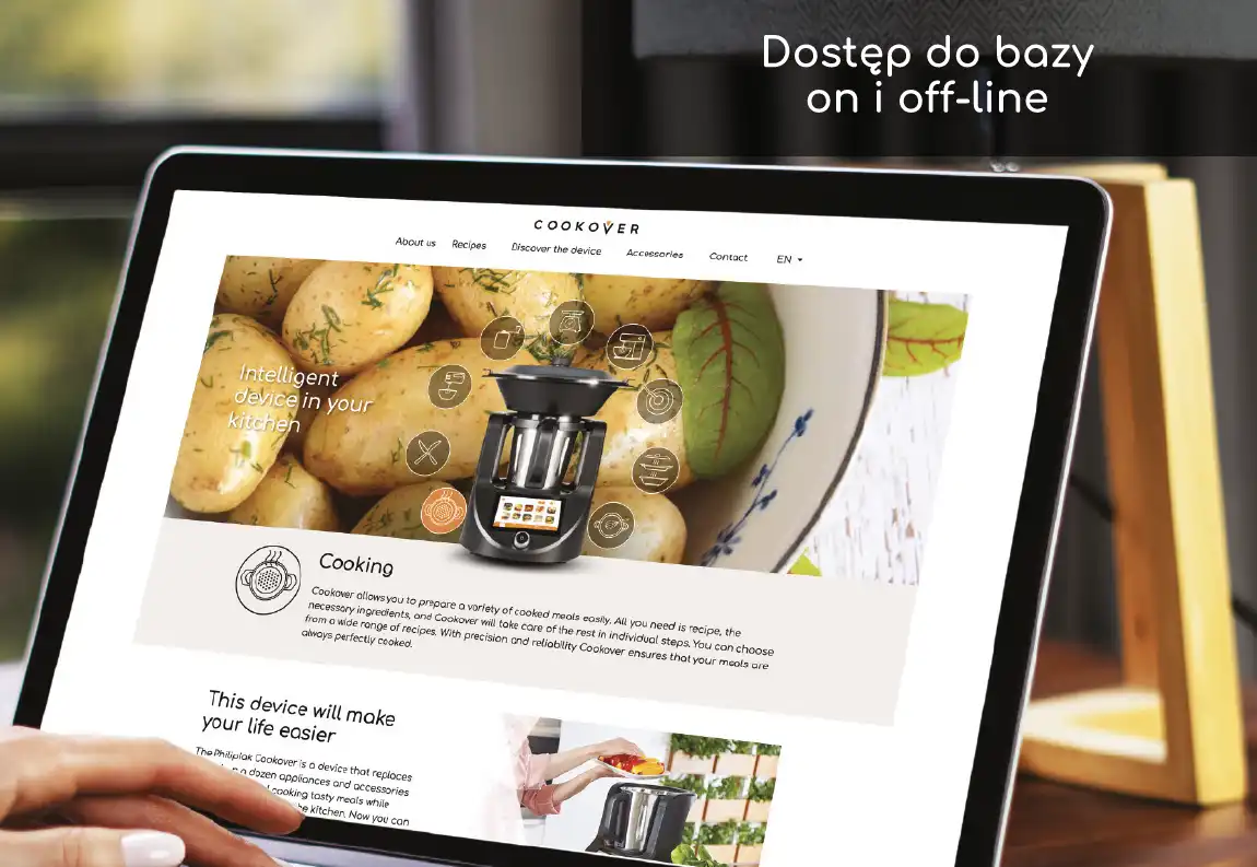Na ekranie tabletu widoczna jest strona internetowa z grafiką przedstawiającą ziemniaki i urządzenie kuchenne z napisem \'Intelligent device in your kitchen\'. W prawym górnym rogu obrazu znajduje się tekst \'Dostęp do bazy on i off-line\'.