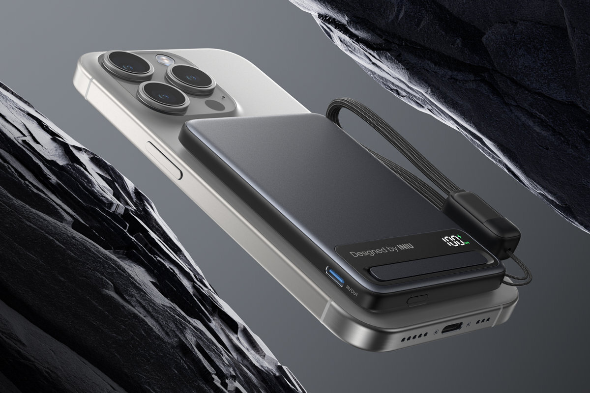 Na obrazie widoczny jest czarny powerbank z napisem \'Designed by INIU\' umieszczony na smartfonie. W tle znajdują się ciemne, skaliste formacje.