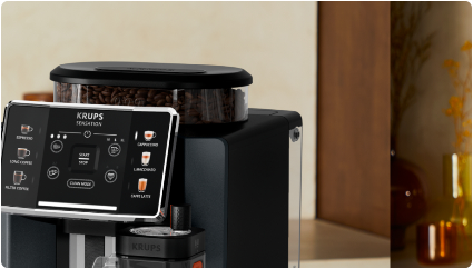 Ekspres do kawy z wyświetlaczem dotykowym, na którym widoczne są opcje takie jak espresso, cappuccino i latte. Na górze urządzenia znajduje się pojemnik z ziarnami kawy.