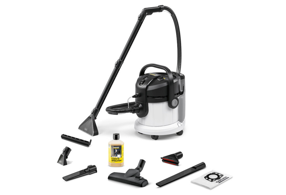 Na obrazie znajduje się odkurzacz piorący z kilkoma akcesoriami, w tym różnymi końcówkami i butelką płynu czyszczącego. Widoczne jest logo \'KARCHER\' na butelce.