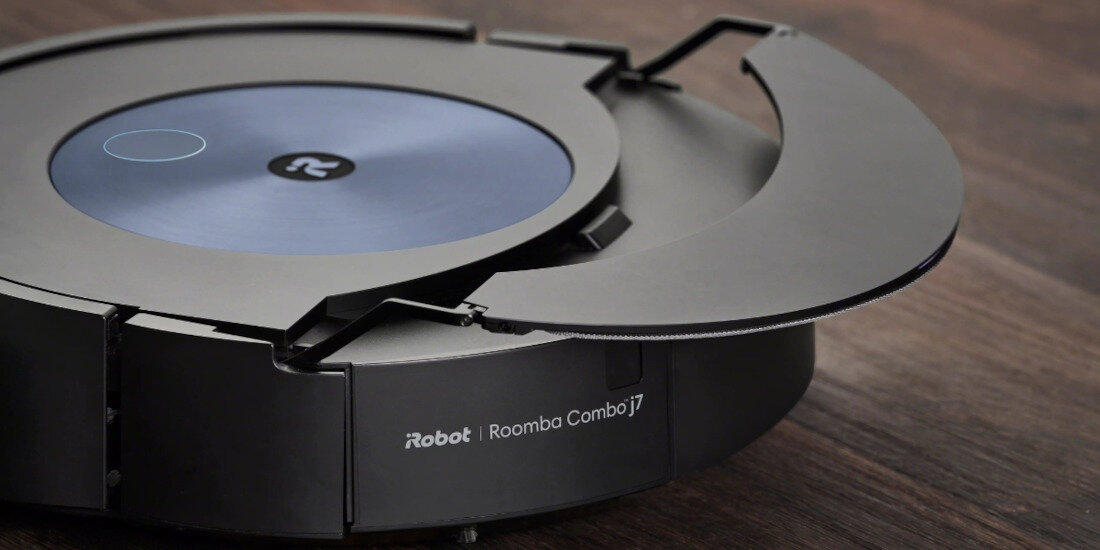 Na drewnianej powierzchni znajduje się robot sprzątający z widocznym logo i napisem \'iRobot Roomba Combo j7\'.
