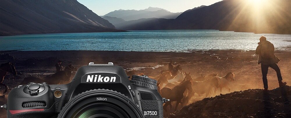 Na pierwszym planie widoczny jest aparat fotograficzny z logo Nikon i oznaczeniem D7500. W tle znajduje się krajobraz z jeziorem, górami i osobą stojącą na brzegu.