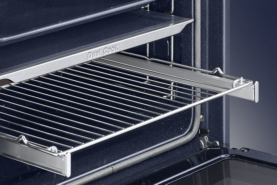 Wnętrze piekarnika z wysuniętą metalową kratką i półką oznaczoną napisem \'Dual Cook\'. Wnętrze jest ciemne, a elementy są wykonane z metalu.