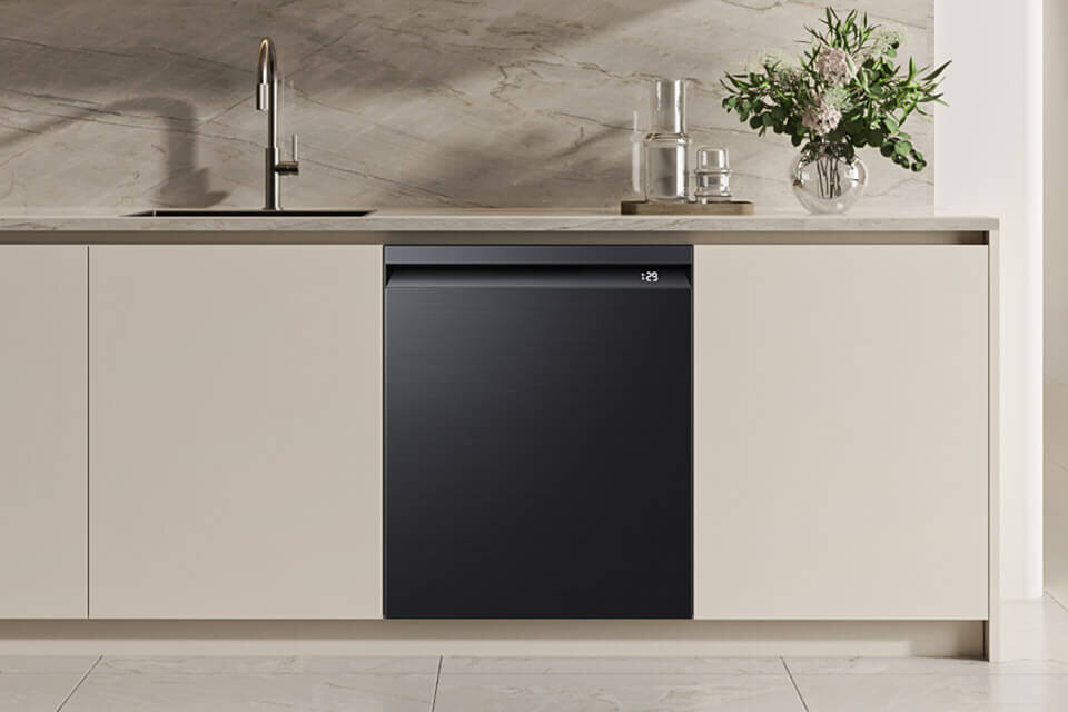 Zmywarka Samsung DW80H73YBUFU1 w ofercie Media Expert Zmywarka w zabudowie kuchennej z czarnym frontem, obok zlewozmywak i wazon z kwiatami na blacie. Na wyświetlaczu zmywarki widoczny jest numer \'129\'.
