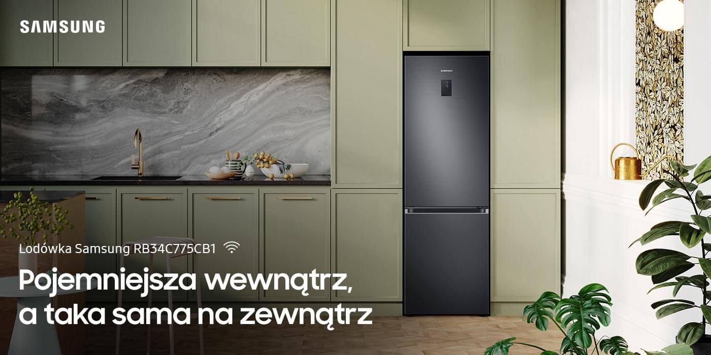 Grafitowa lodówka Samsung RB34C775CB1 EF AI No Frost stoi w eleganckiej kuchni z zielonymi szafkami i marmurowym blatem. Na obrazie widoczny jest tekst: \'Pojemniejsza wewnątrz, a taka sama na zewnątrz\'.