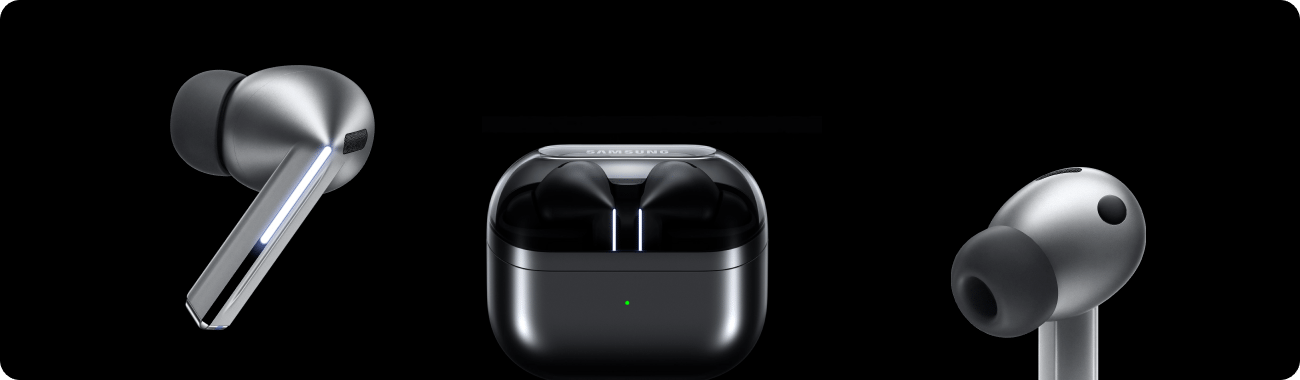 Na obrazie widoczne są srebrne słuchawki dokanałowe oraz etui ładujące z logo \'SAMSUNG\'. Słuchawki mają nowoczesny design z błyszczącymi elementami, a etui posiada małą zieloną diodę sygnalizacyjną.