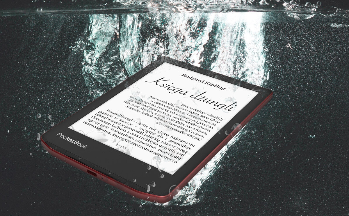 Czytnik e-booków zanurzony w wodzie, na ekranie widoczny tekst \'Rudyard Kipling Księga dżungli\'. Na obudowie znajduje się logo \'PocketBook\'.