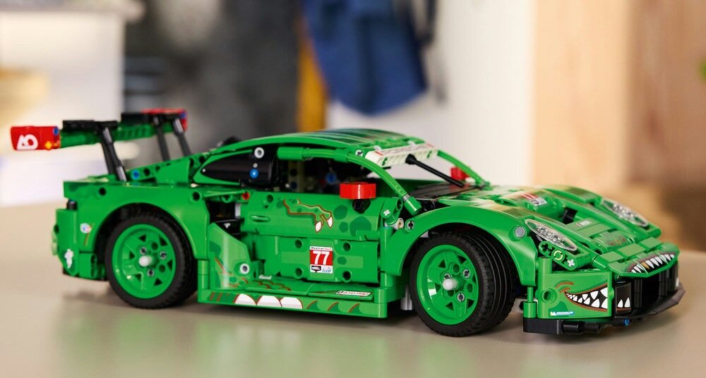 Zielony model samochodu LEGO z widocznymi detalami, takimi jak naklejki i spojler. Na boku widoczny numer 77 oraz wzory przypominające zęby i oczy.