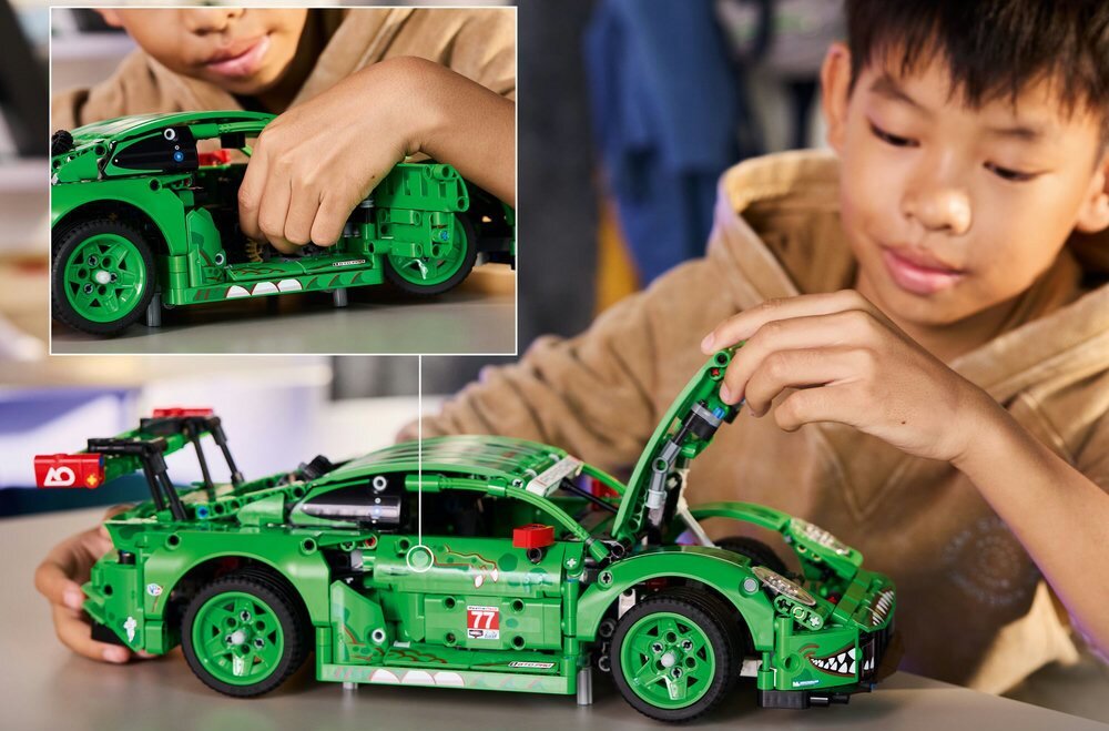 Dziecko bawi się zielonym modelem samochodu z klocków LEGO, który ma otwartą maskę. Na samochodzie widoczne są naklejki z numerem 77 i logo \'AO\'.