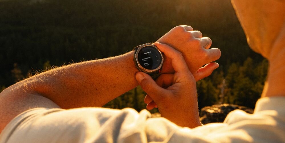 Smartwatch Amazfit T-Rex Dual Solar 51 mm Black Magma na ręce turysty o zachodzie słońca – wyszukiwanie punktów POI woda i schronienie, punkty kontrolne, udostępnianie aktywności na żywo